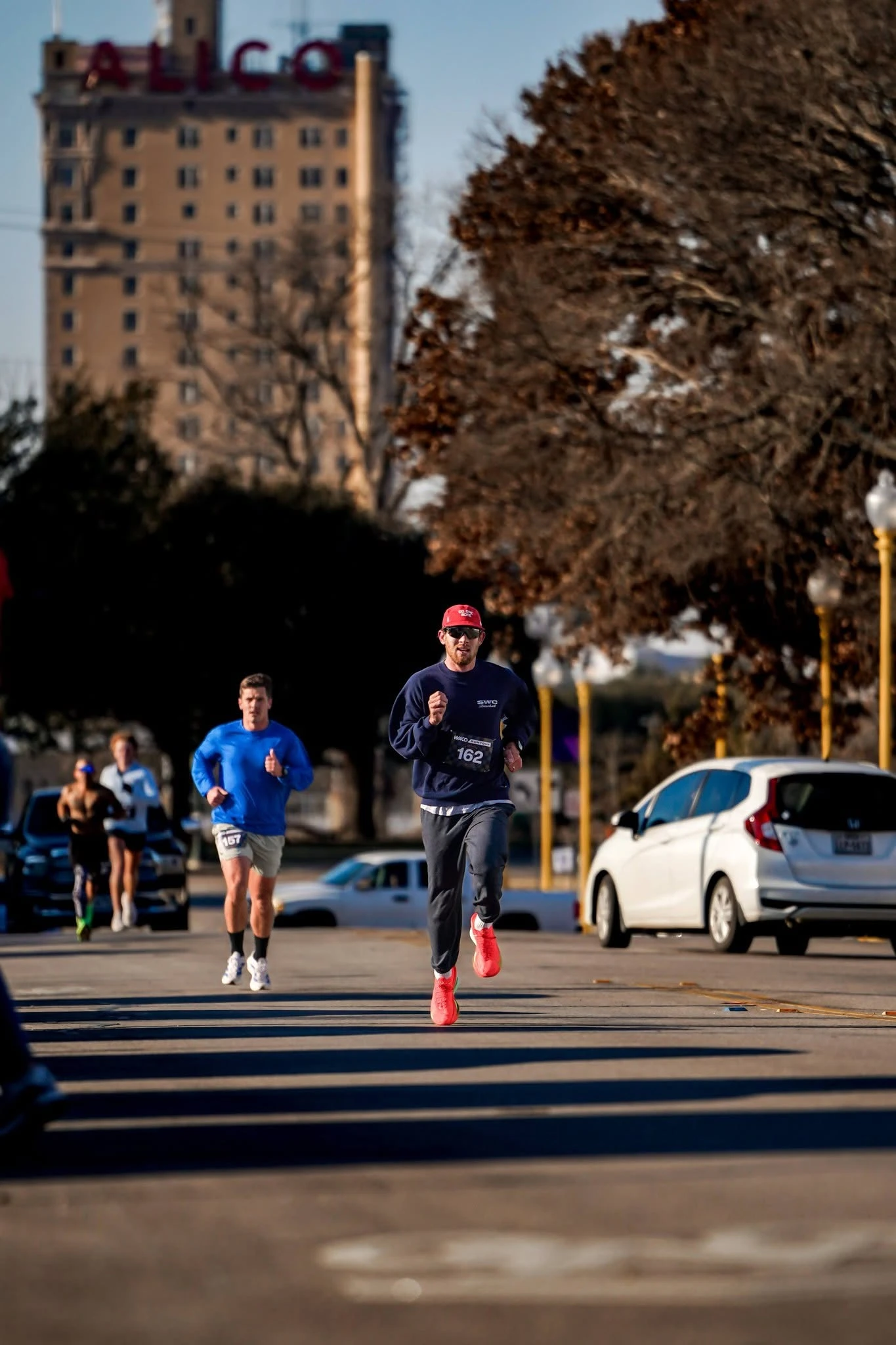 Runners racing through downtown Waco beneath the ALICO building
